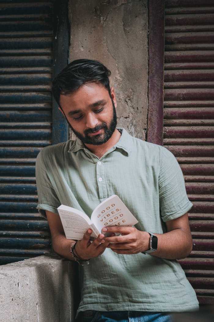 A man reading a book in front of a building
